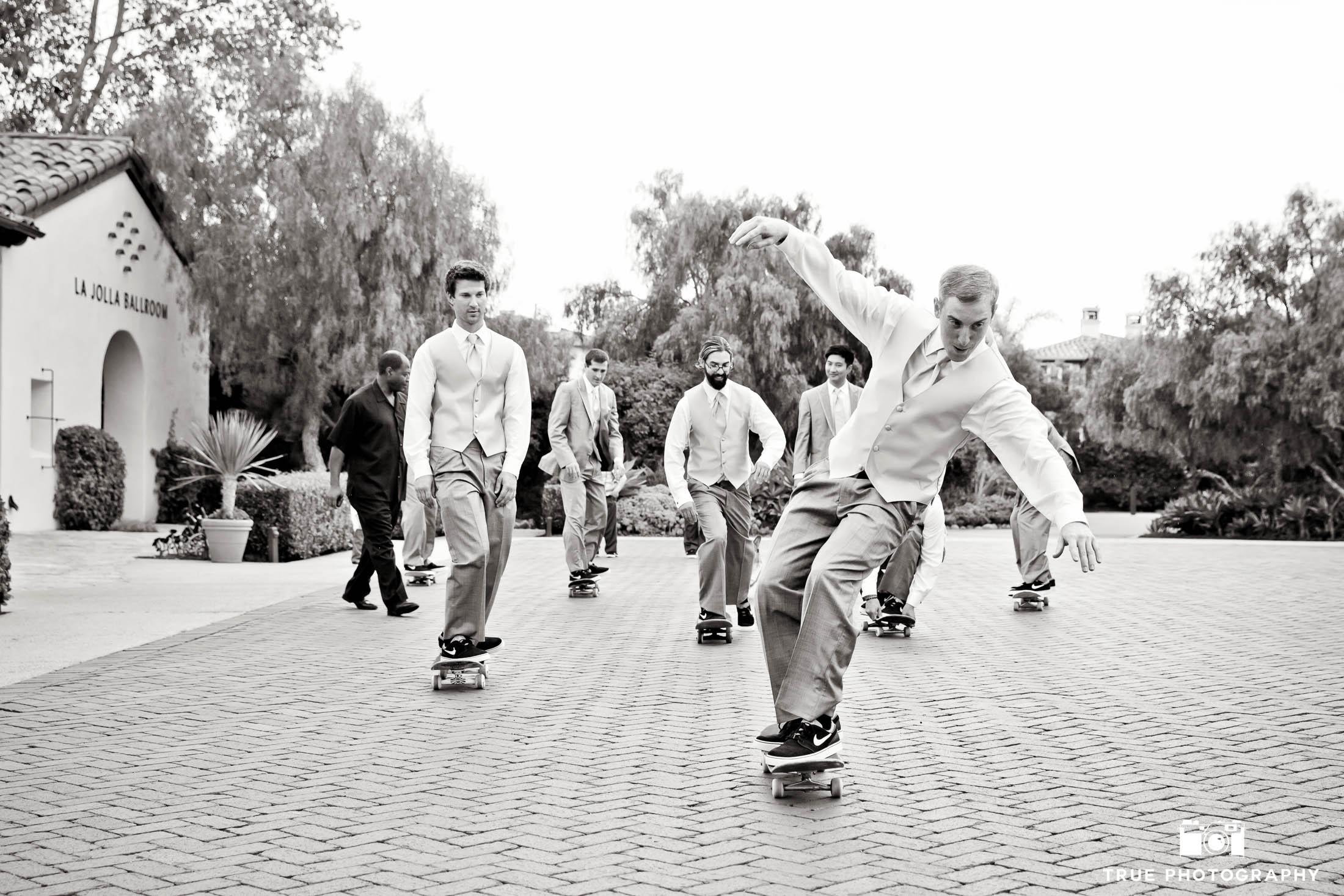 Groomsmen skateboarding down street