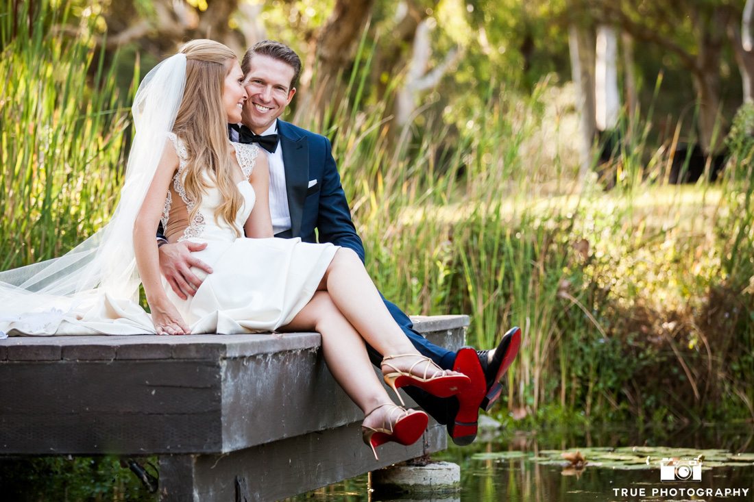 Bride and groom wearing Louboutin shoes sitting at the edge of dock