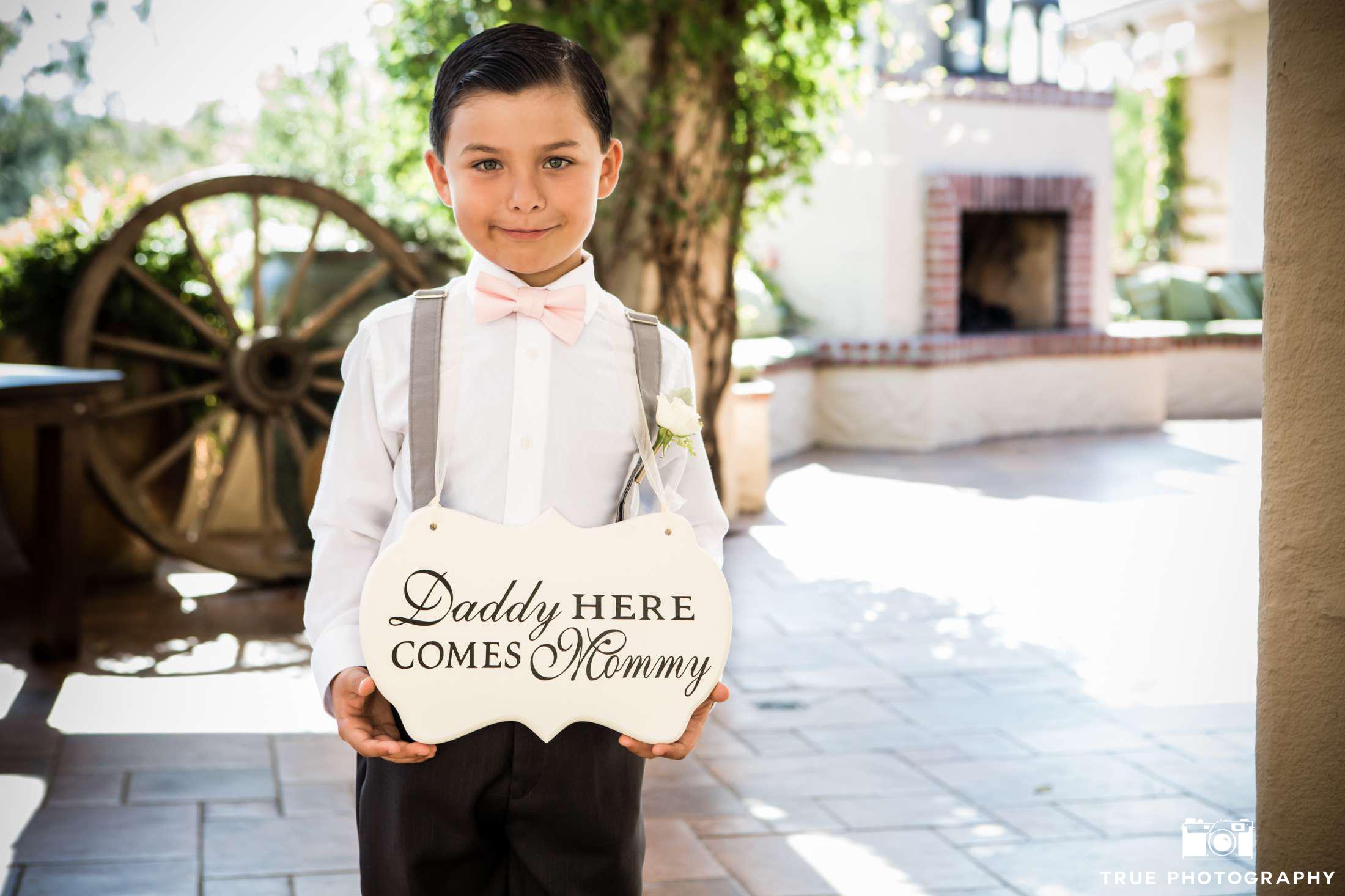 ring bearer in pink bow tie with sign