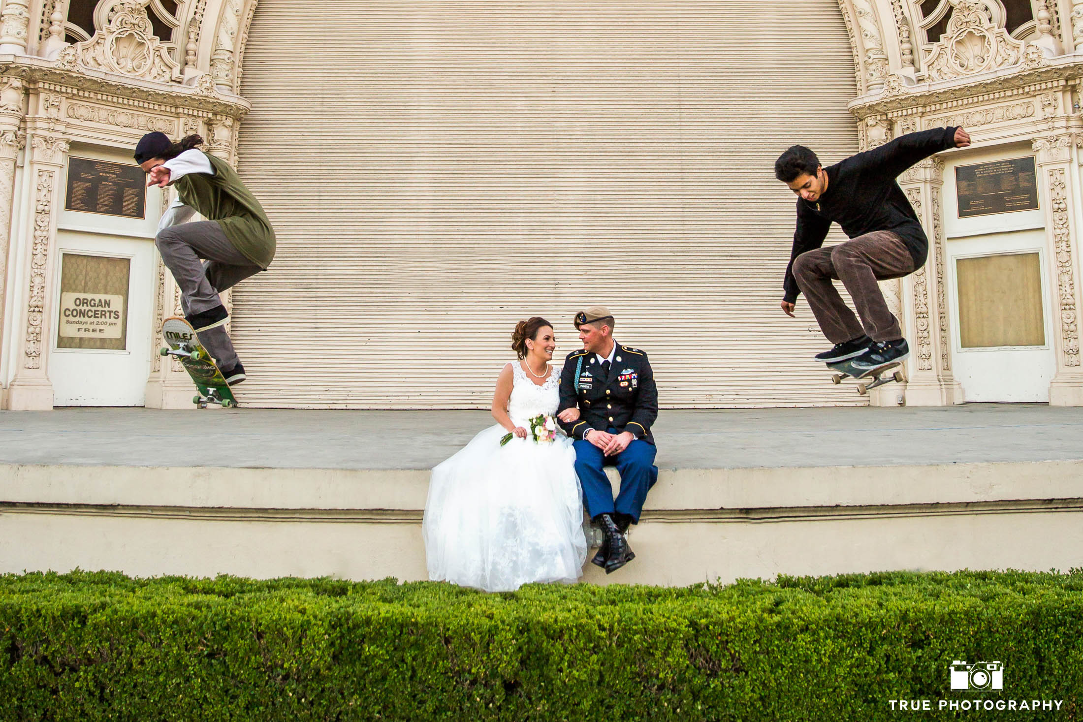 Bride and Groom sit on ledge as skateboards do tricks around them