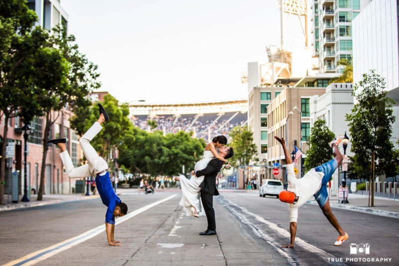 Groom picks up and kisses bride in middle of street by dances in downtown san diego