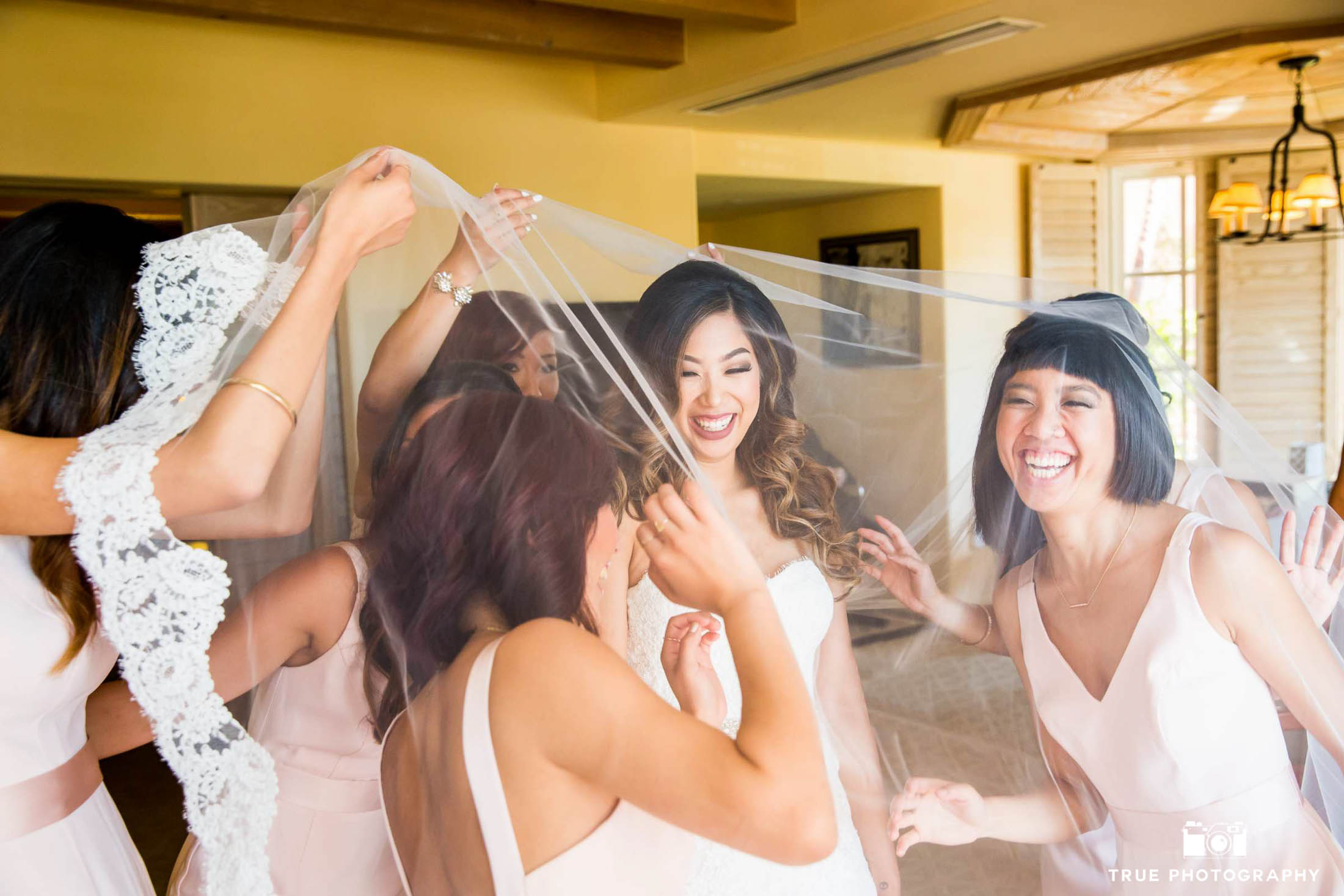 Bride and bridesmaids have fun while getting ready.